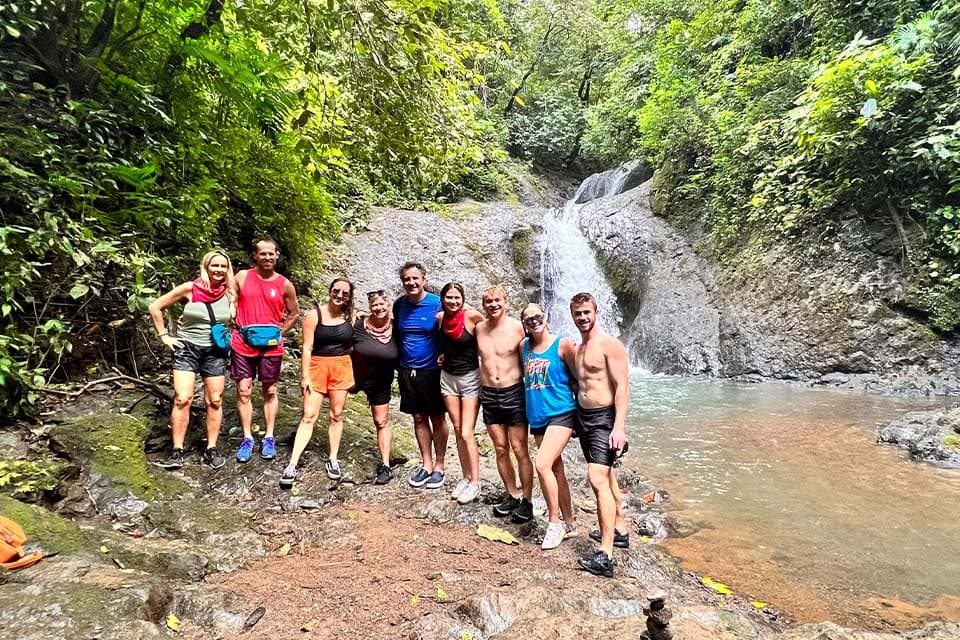 The group standing on the rocks in front of a waterfall pool at the turnaround point.