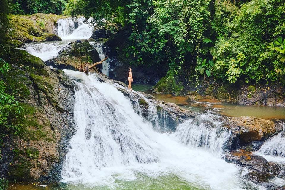 The upper pools, water braiding over rock into a green plunge pool with a swimmer above it.