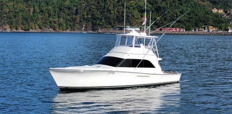 Crushem under way in deep blue water, the hills of the coast behind her.