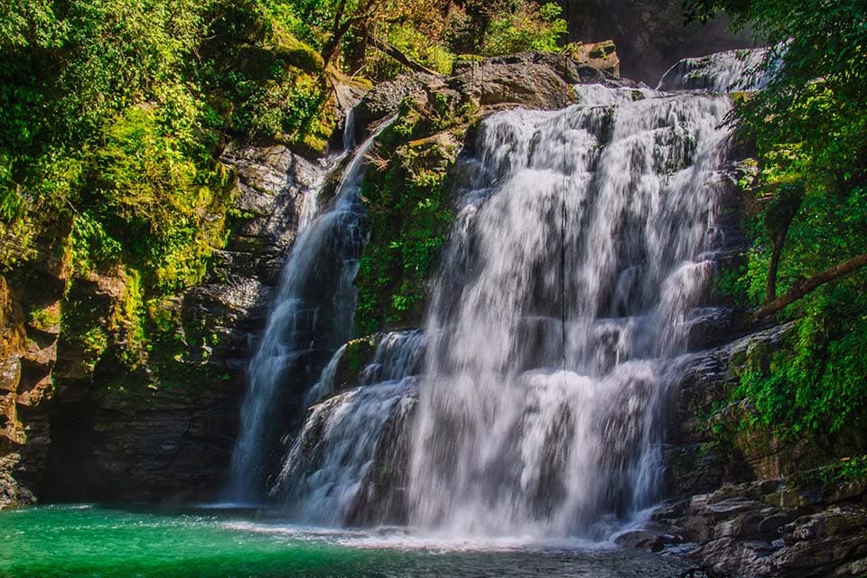 The falls in full flow into a jade-green pool, forest crowding both banks.