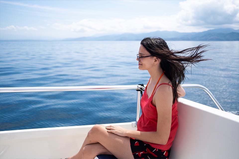 A guest on the side deck watching the coastline go past as the boat crosses the gulf.