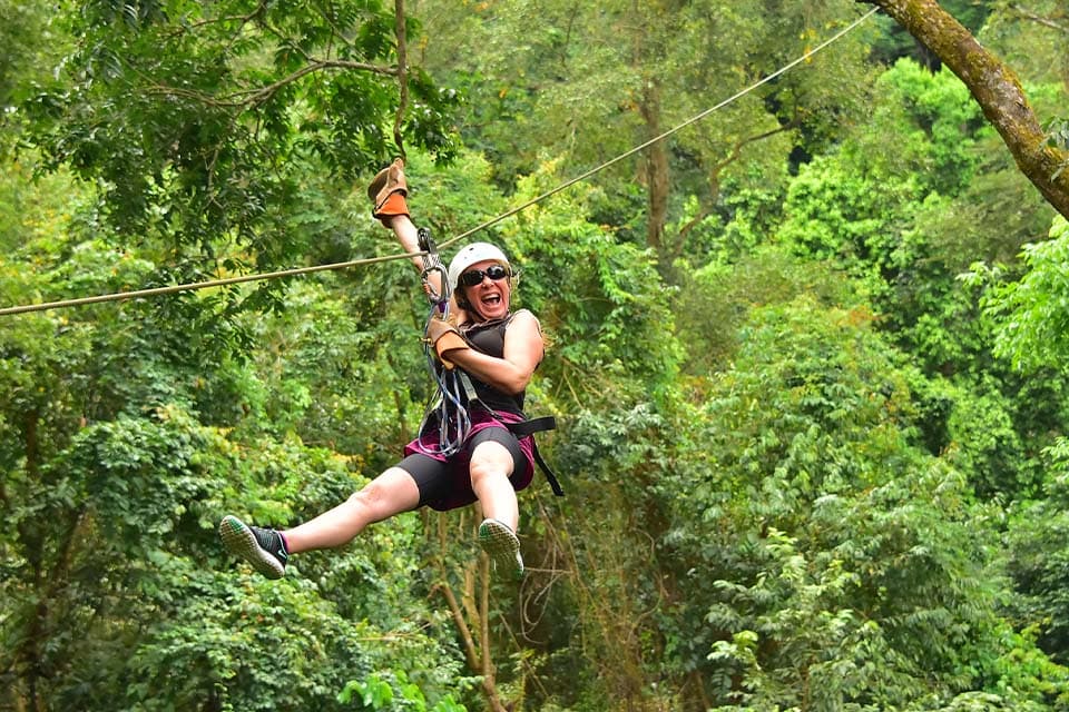 A rider mid-flight over the canopy, legs out, laughing.